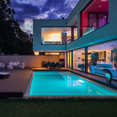 Modern Smart Home with RGB lighting controls and pool lighting outdoor technology in connected home Modern villa with colored led lights at night